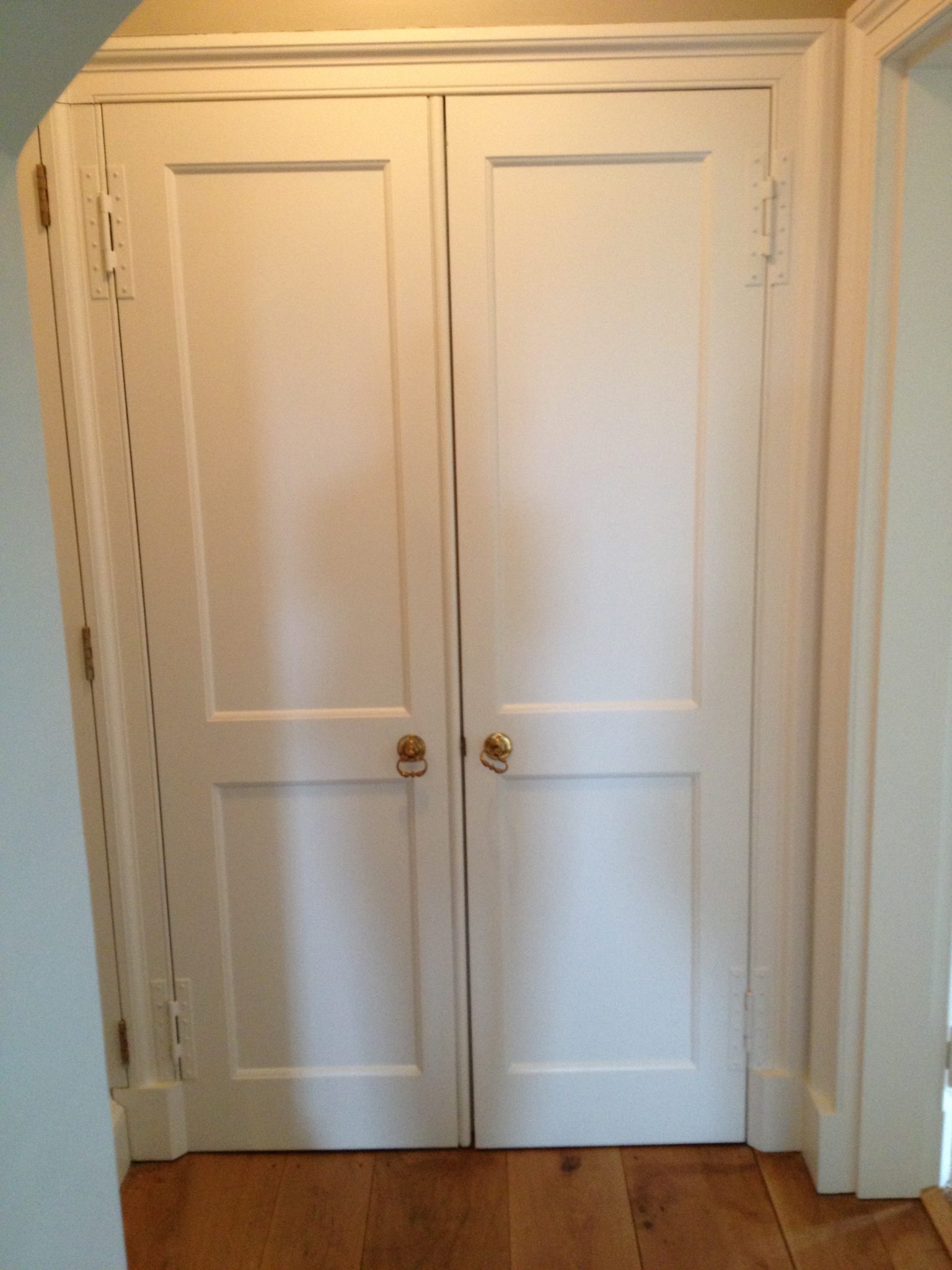 Symmetrical double doors open to reveal a single doorway and a hidden cupboard
