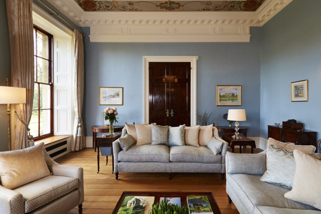 Blue upholstered sofa in a Georgian living room with tall sash windows and decorative cornicing.