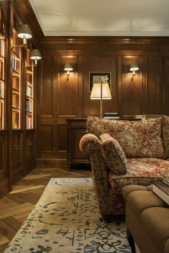 Georgian library with wood panelling and red tapestry-pattern upholstered sofa.