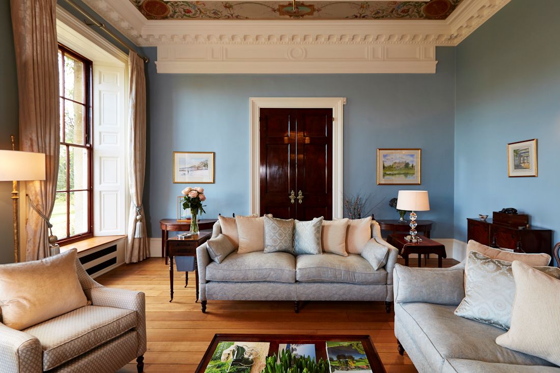 Blue upholstered sofa in a Georgian living room with tall sash windows and decorative cornicing.